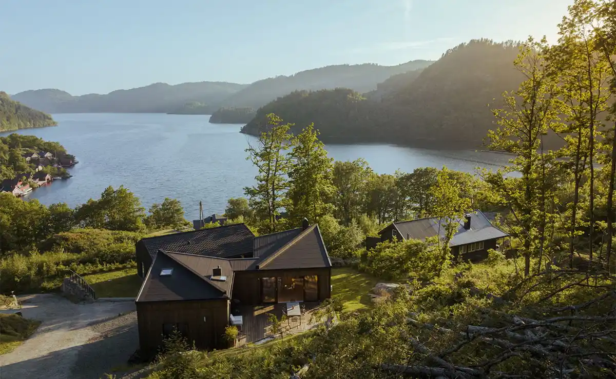 Kebony tømmerkledd arkitekthytte ved en innsjø på landsbygda i Norge